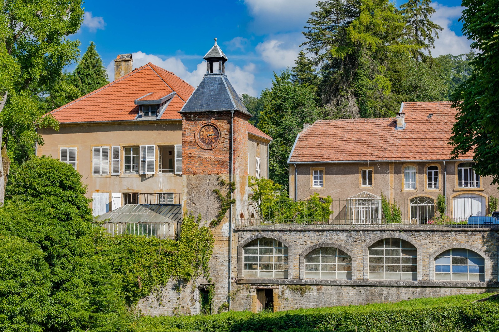 Vue d'ensemble des bâtiments des Forges de Buré d'Orval, avec la tour de l'horloge au centre.